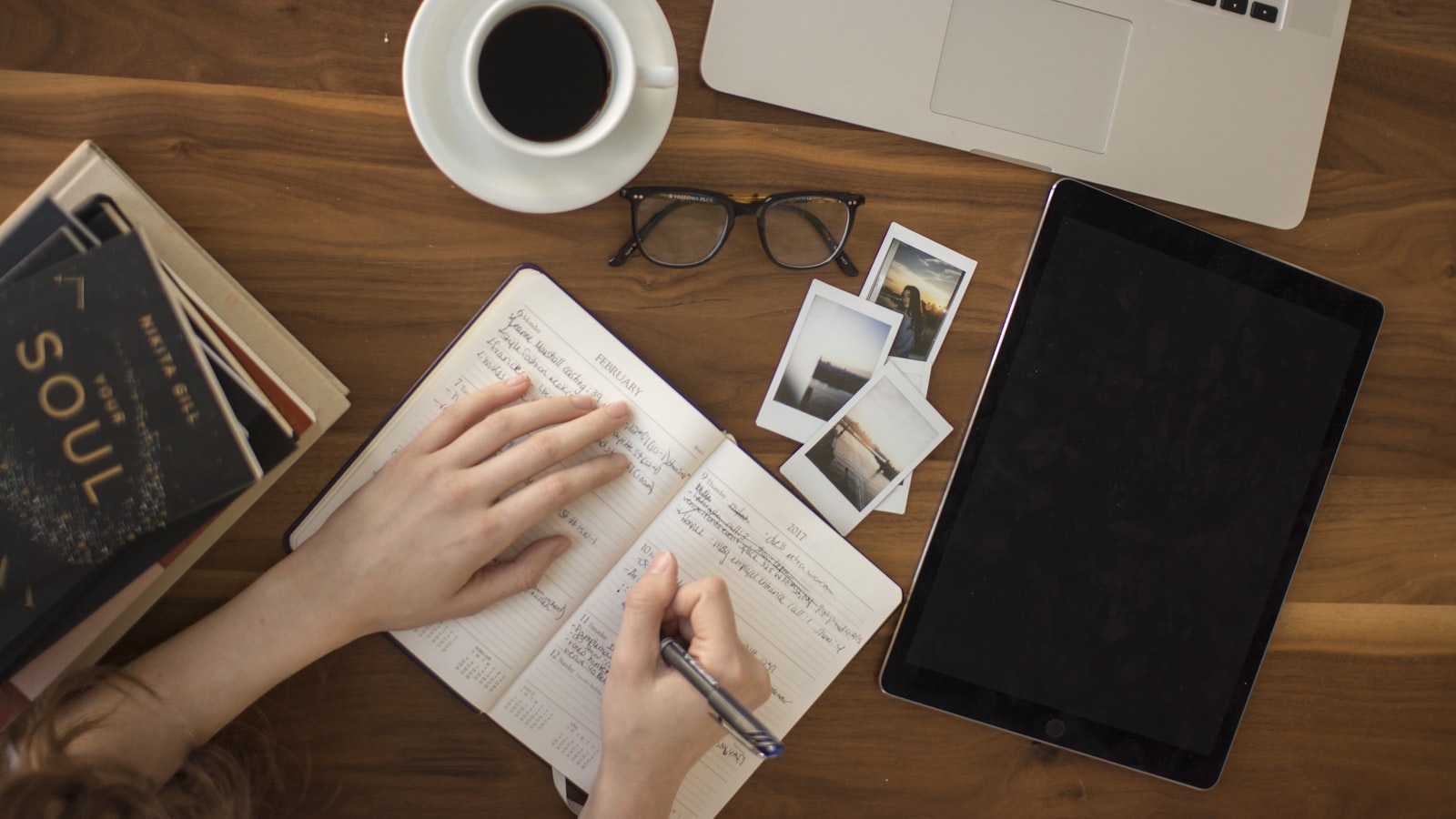 A person at a desk pausing over study materials and a laptop
